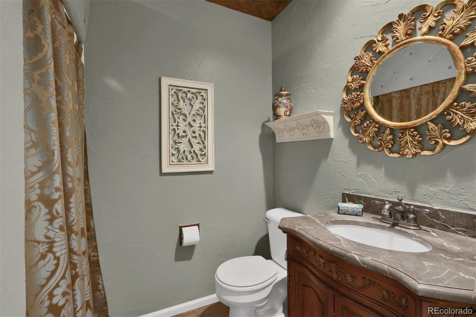 10115 Spring Water Court Highlands Ranch, CO 80129 - Photo 13 of 35 a bathroom with a granite countertop toilet a sink and a mirror