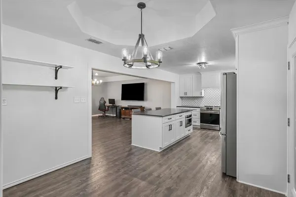 a kitchen with stainless steel appliances granite countertop a refrigerator oven a sink dishwasher and white cabinets with wooden floor