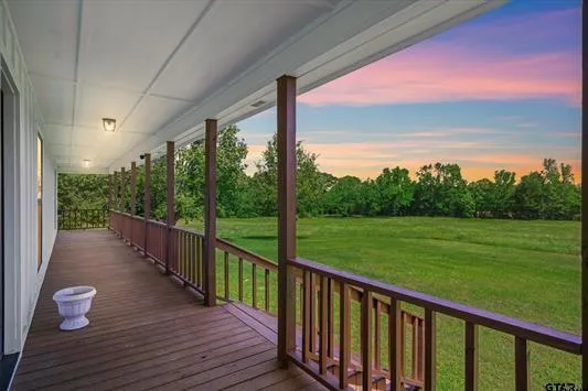 a view of a patio with wooden floor next to a yard