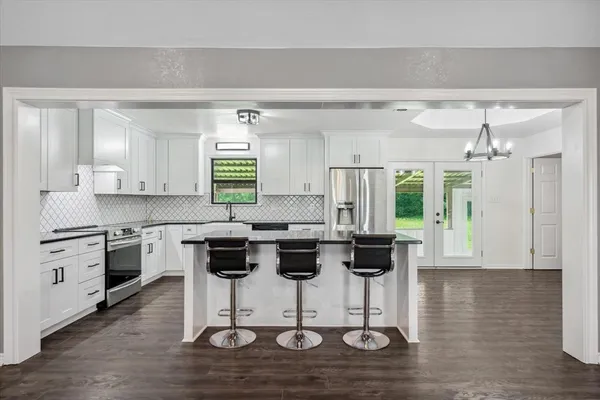 a kitchen with stainless steel appliances granite countertop a stove top oven a refrigerator a sink and dishwasher with wooden floor
