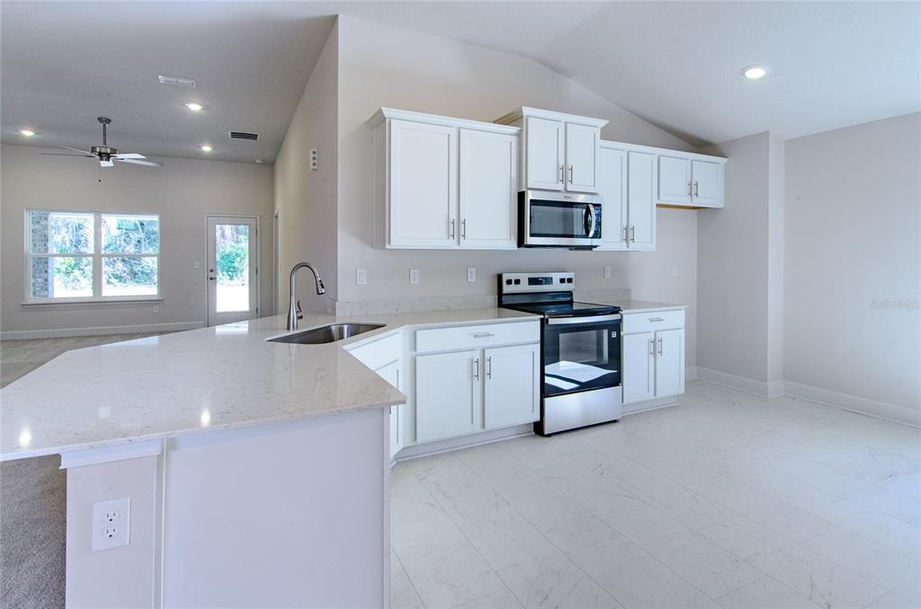 67 Sedgwick Trail Palm Coast, FL 32164 - Photo 11 of 27 a kitchen with stainless steel appliances a sink a stove a refrigerator cabinets and a window