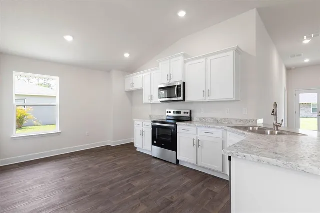 a kitchen with granite countertop white cabinets and wooden floor
