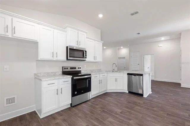 a kitchen with granite countertop white cabinets and stainless steel appliances