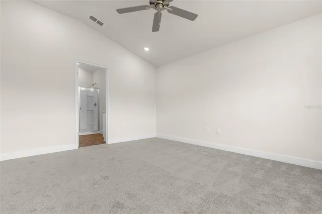 an empty room with a ceiling fan and carpet