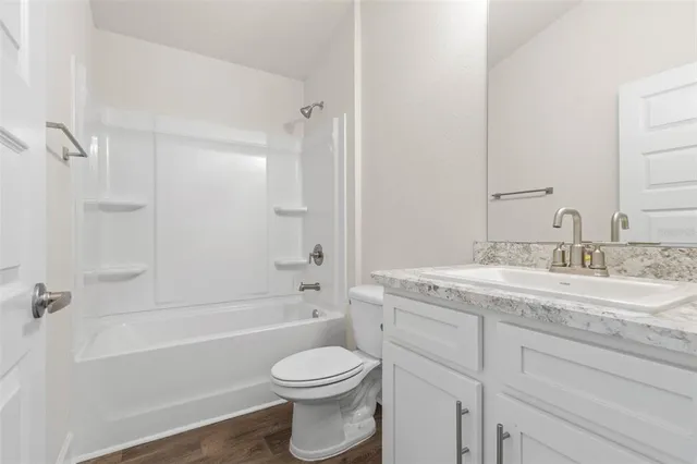 a bathroom with a granite countertop toilet a sink and a bathtub