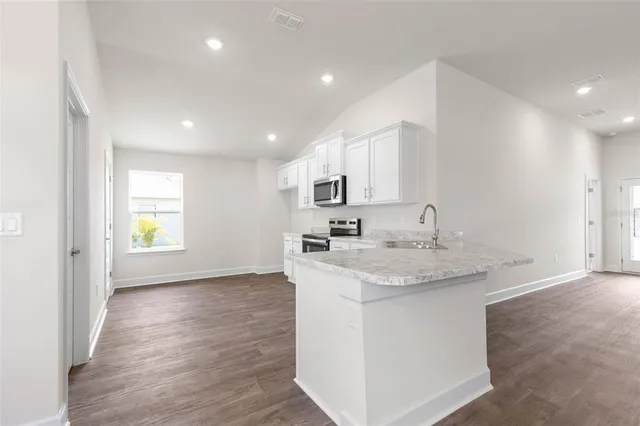 a view of a kitchen counter space a sink wooden floor and a window