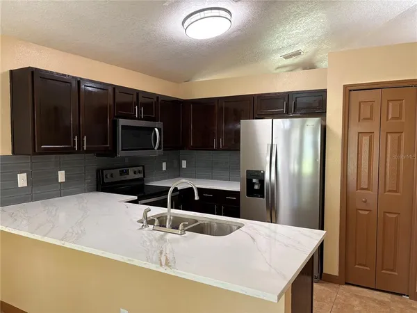 a kitchen with stainless steel appliances wooden cabinets a refrigerator and a sink