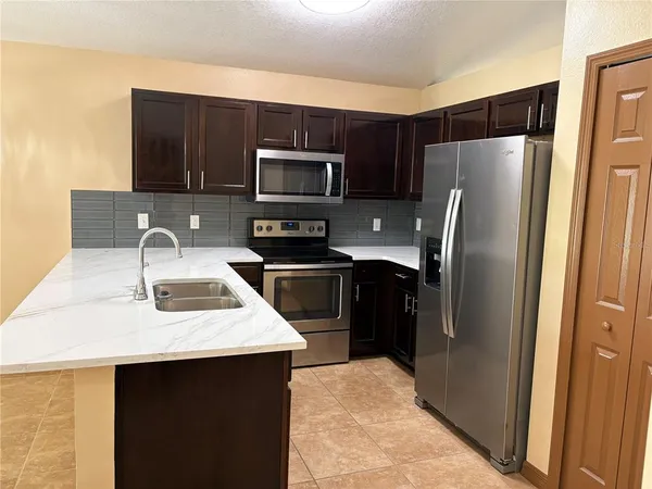 a kitchen with stainless steel appliances a refrigerator a sink a stove a microwave and wooden cabinets