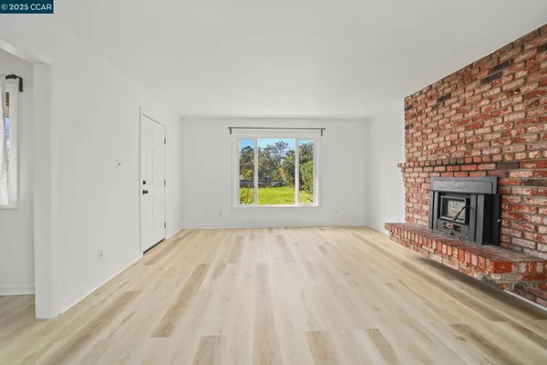 a view of an empty room with window and fire place
