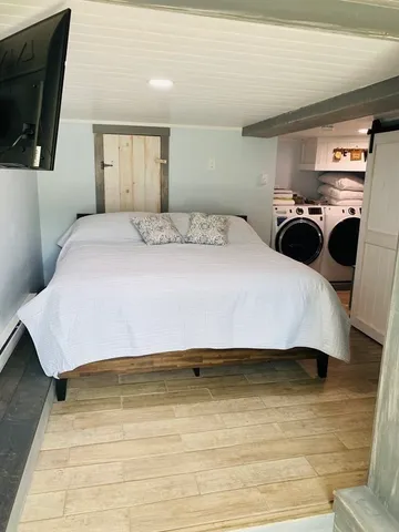 a bedroom with a bed and a flat tv screen next to a window
