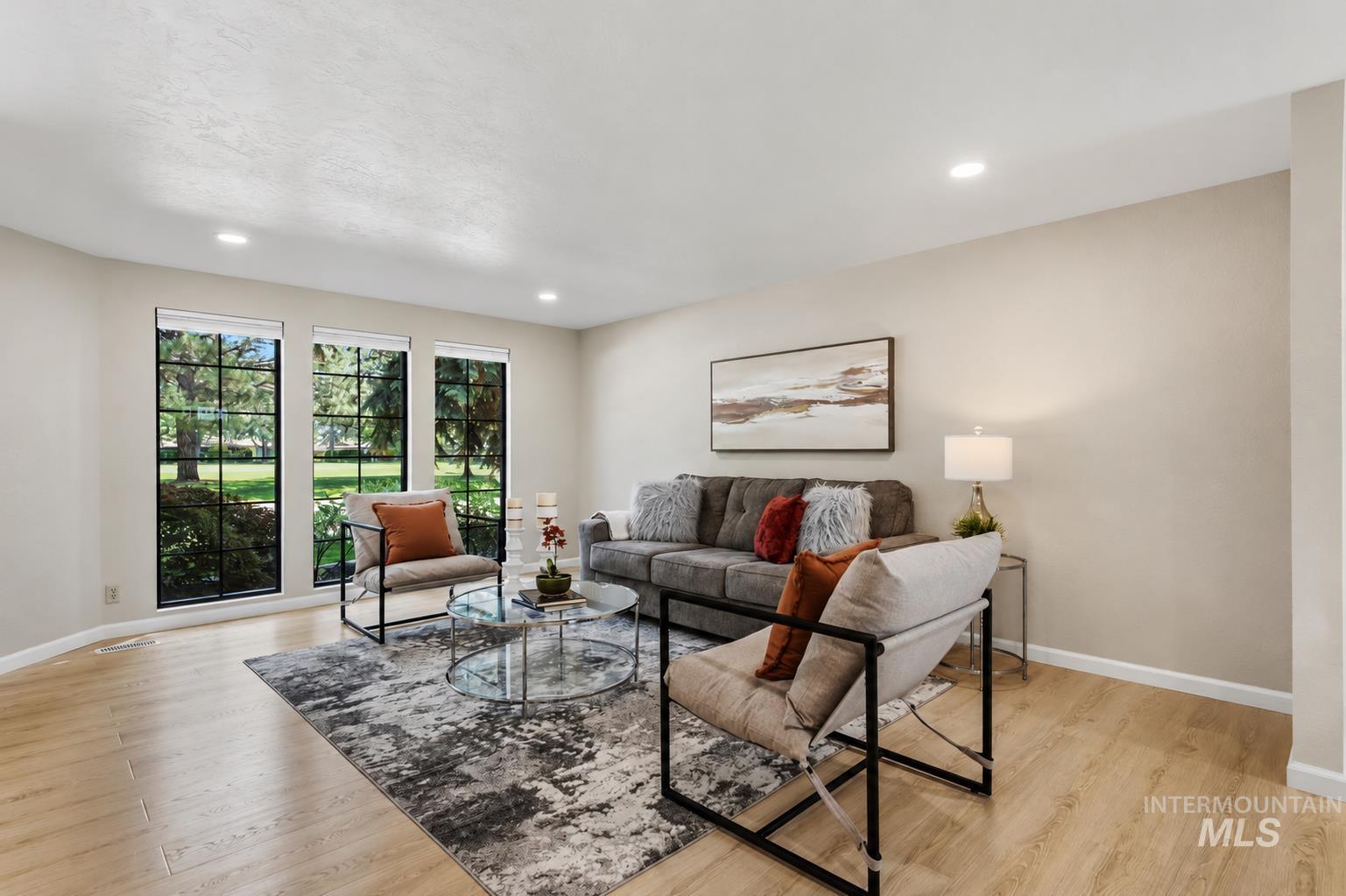 599 Pebble Beach Way Eagle, ID 83616 - Photo 5 of 44 Living area featuring three large grid-pattern windows overlooking exterior greenery, recessed lighting, and light wood-finish flooring