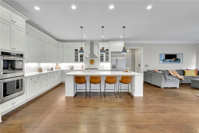 a kitchen with stainless steel appliances granite countertop a stove top oven a sink dishwasher and a refrigerator with wooden floor