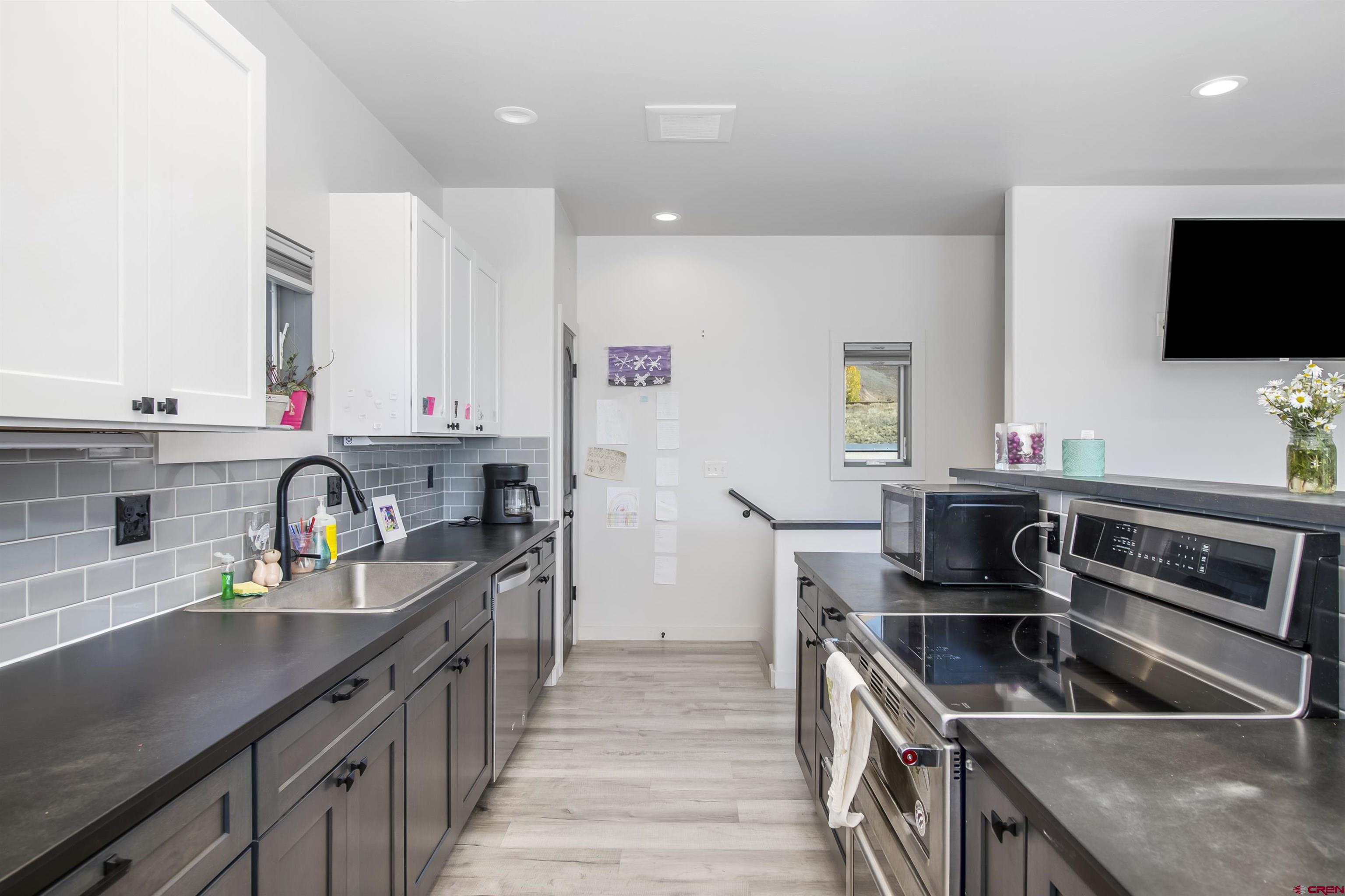 363 Cement Creek Road, Unit 3 Crested Butte, CO 81224 - Photo 3 of 34 a kitchen with stainless steel appliances a sink dishwasher a stove a microwave oven with wooden cabinets and floor