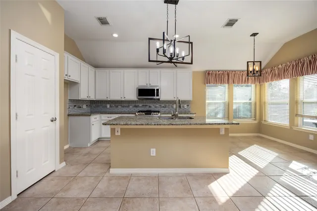 a large kitchen with kitchen island white cabinets and stainless steel appliances