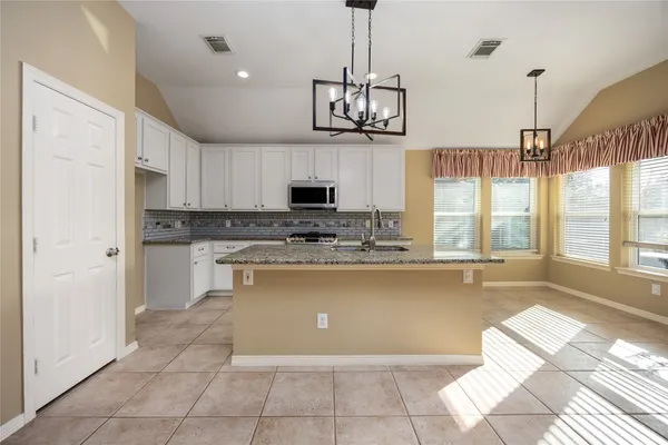 a large kitchen with kitchen island white cabinets and stainless steel appliances