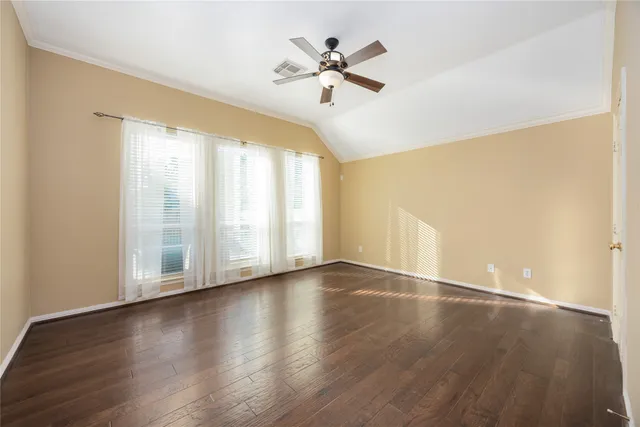 an empty room with wooden floor fan and windows