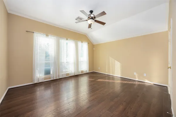 an empty room with wooden floor fan and windows