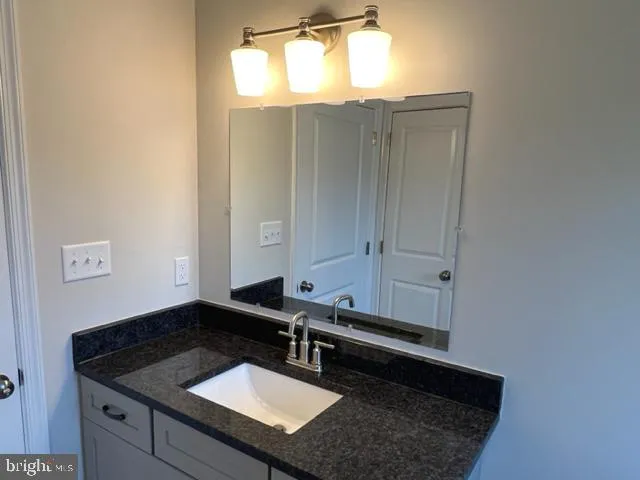 a bathroom with a sink vanity granite and a mirror