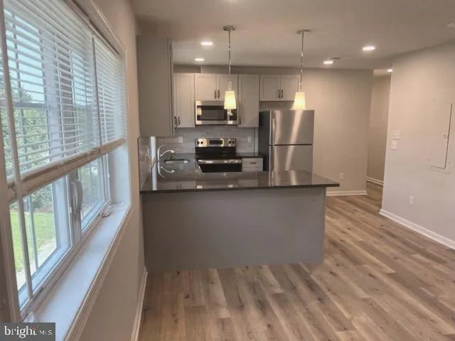 a view of a kitchen with stainless steel appliances wooden floor and large window