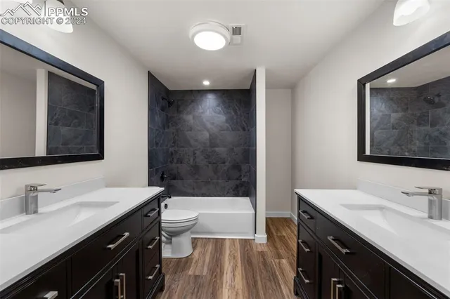 an empty room with wooden floor a ceiling fan and windows
