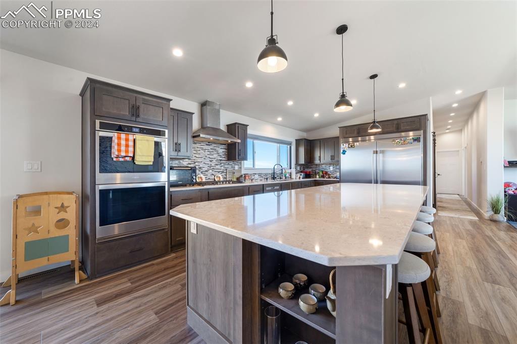 38640 Jones Road Rush, CO 80833 - Photo 10 of 41 a large kitchen with kitchen island a large island a stove a refrigerator and a dining table with wooden floor