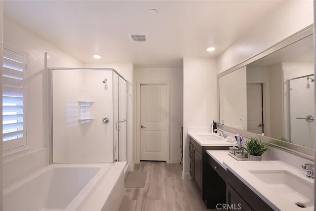 a bathroom with a tub sink double vanity granite tub shower and mirror