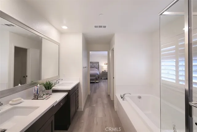 a en suite spacious bathroom with a tub double vanity sink and mirror