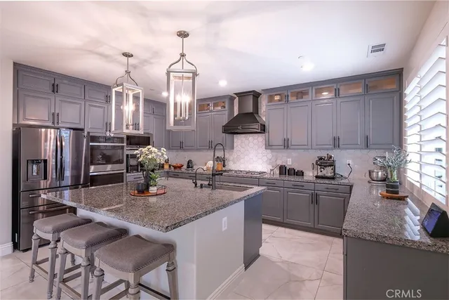 a kitchen with granite countertop kitchen island stainless steel appliances a sink a stove a refrigerator cabinets and chairs