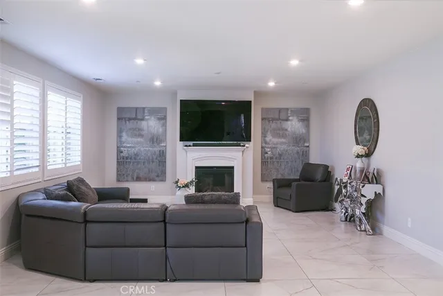 a living room with furniture a fireplace a flat screen tv and a large window