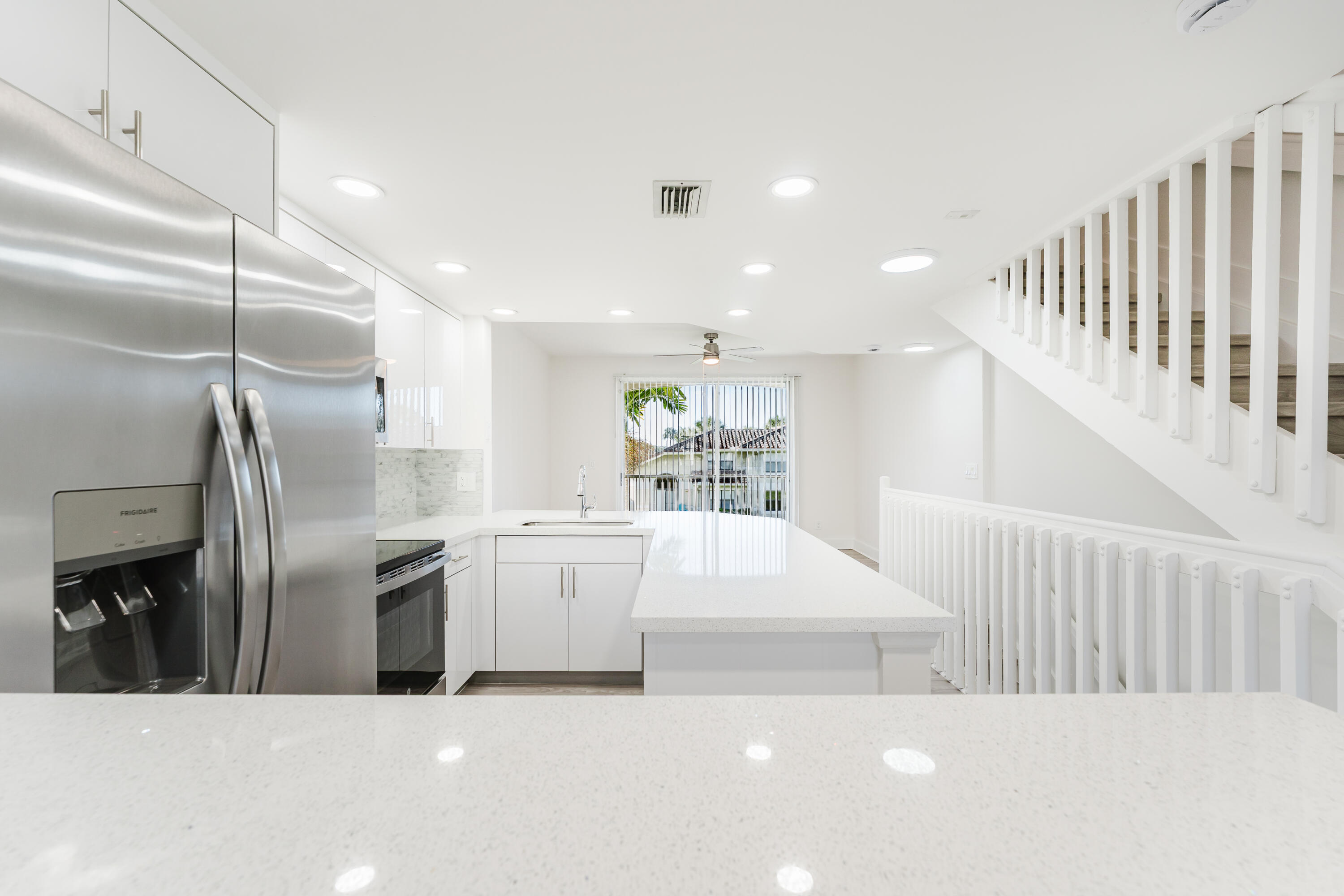 20889 St Andrews Boulevard Boca Raton, FL 33433 - Photo 8 of 46 a kitchen with stainless steel appliances kitchen island granite countertop a refrigerator a sink a stove and white cabinets with wooden floor