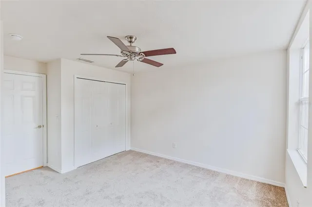 an empty room with a fan & a window