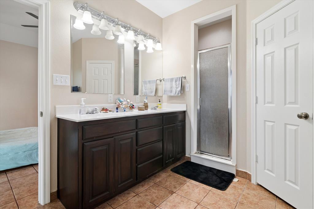 6005 Hawkeye Road Krum, TX 76249 - Photo 16 of 27 Bathroom featuring a double vanity with dark wood cabinetry and a white countertop, a mirror, and overhead vanity lighting