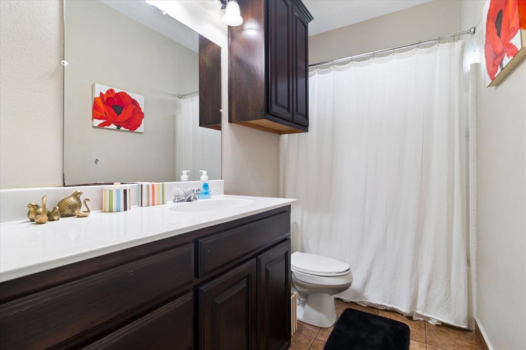 6005 Hawkeye Road Krum, TX 76249 - Photo 20 of 27 Bathroom featuring a dark wood-finish vanity with ample storage, white countertop with an integrated sink, and an overhead dark wood-finish cabinet
