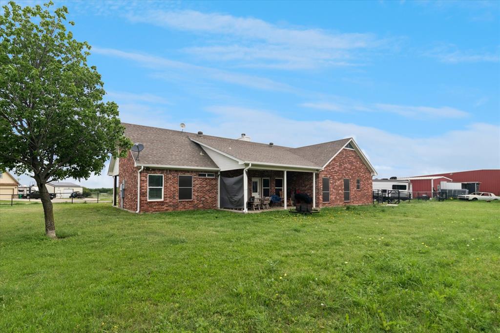 6005 Hawkeye Road Krum, TX 76249 - Photo 22 of 27 Expansive green lawn surrounds a brick-exterior residence with a covered patio area