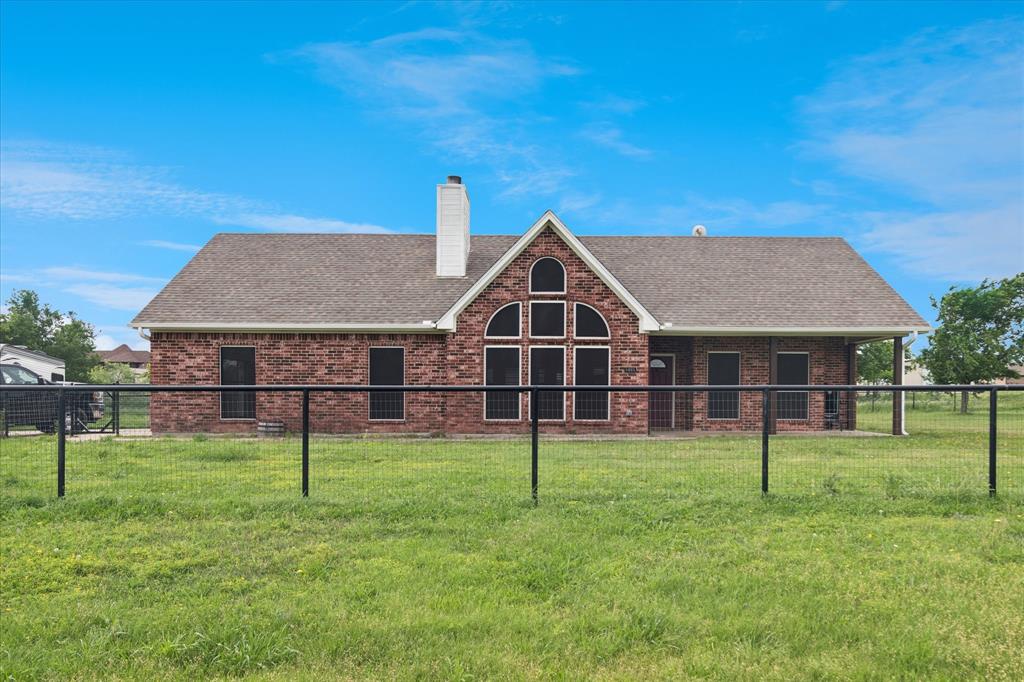 6005 Hawkeye Road Krum, TX 76249 - Photo 8 of 27 Red brick exterior with a prominent gabled architectural feature, arched and rectangular windows, a white chimney, a covered porch, and a perimeter fence