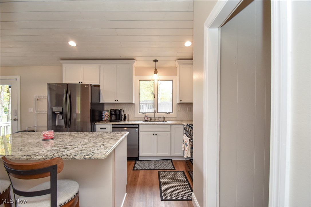 631 Carson Salt Springs Road Warren, OH 44481 - Photo 11 of 39 Kitchen with wood-type flooring, appliances with stainless steel finishes, a wealth of natural light, and decorative light fixtures