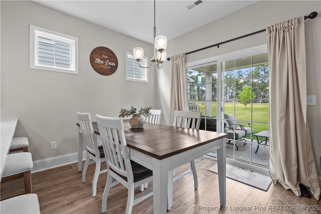 479 Kerr Lake Road Aberdeen, NC 28315 - Photo 11 of 43 a dining room with wooden floor a chandelier a wooden table and chairs