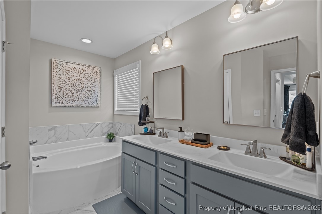 479 Kerr Lake Road Aberdeen, NC 28315 - Photo 19 of 43 a bathroom with a tub sink double vanity and mirror