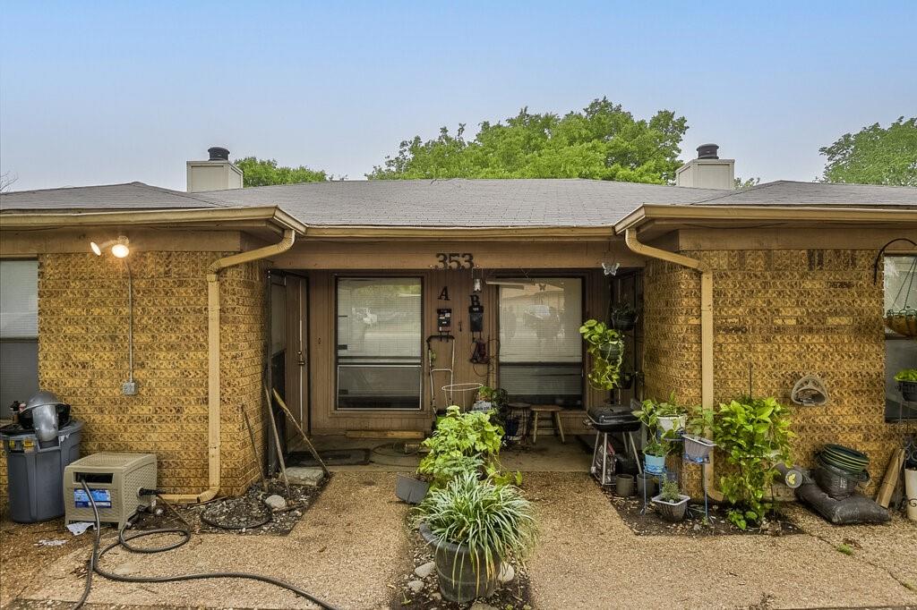 Doorway to property with a chimney, brick siding, and a shingled roof