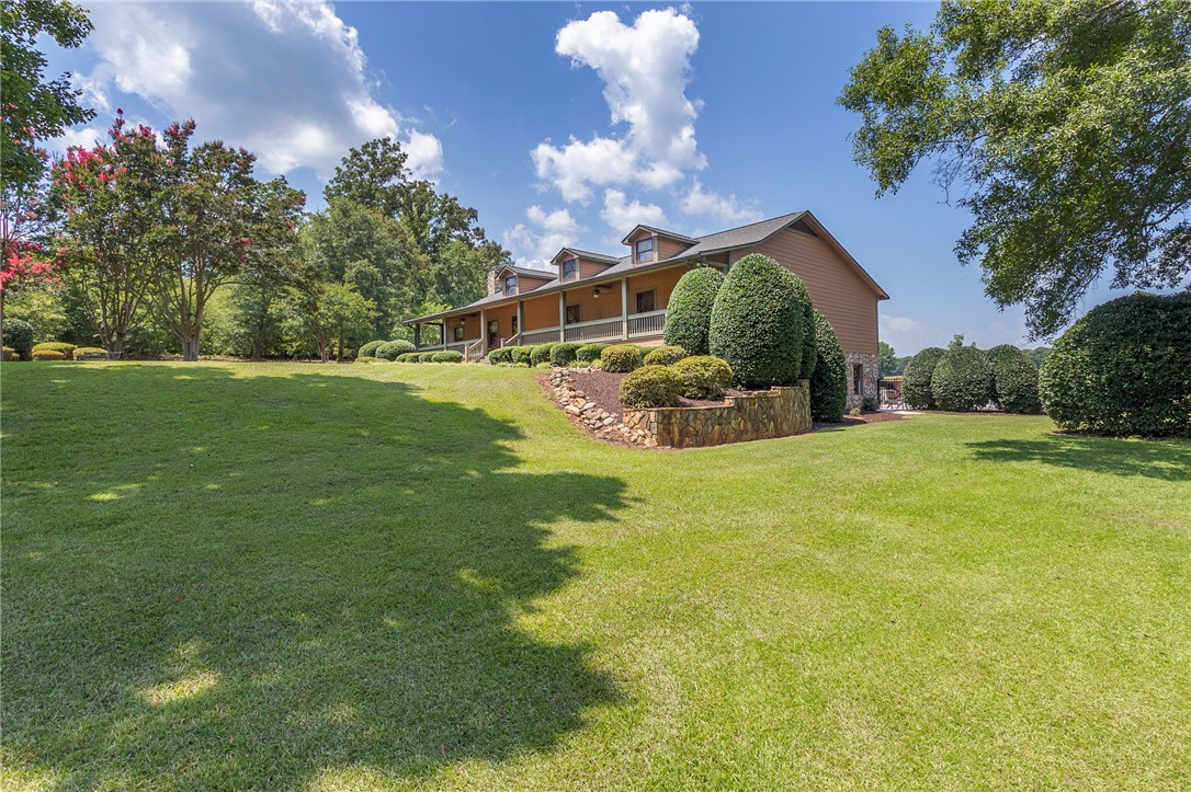 911 State Rd S-4-203 Belton, SC 29627 - Photo 5 of 49 A gracefully designed residence nestled on a verdant hill, offering ample outdoor space and mature landscaping.