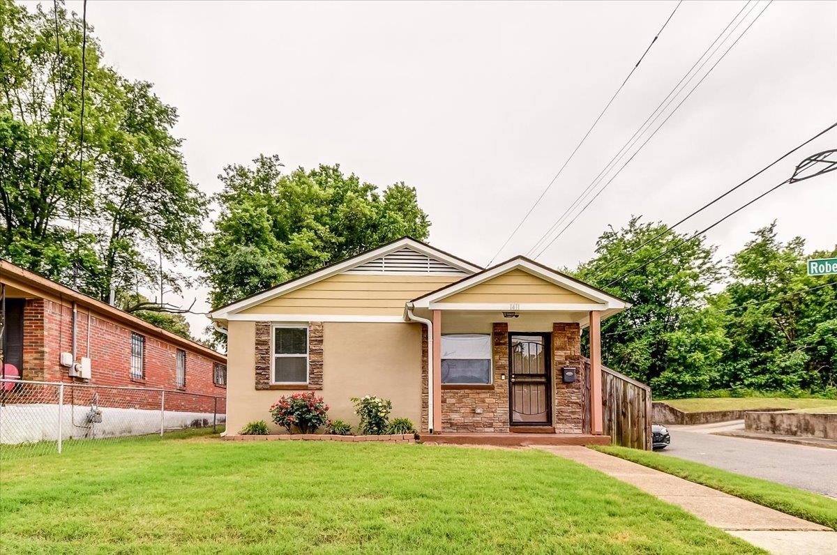 1411 Roberts Road Memphis, TN 38106 - Photo 2 of 24 Single-story residence featuring a stucco exterior with stone accents, a covered front porch, and a well-maintained lawn