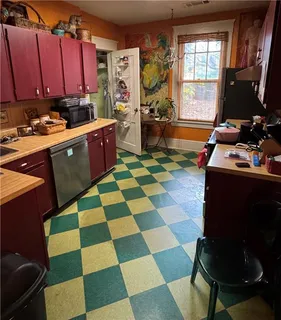 a room with a black white checkered floor kitchen island a stove a sink dishwasher and a computer table