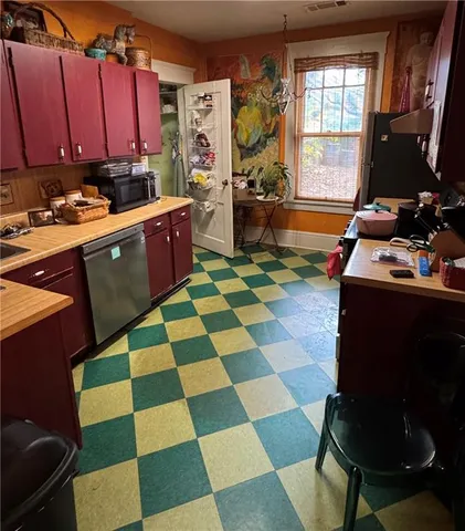 a room with a black white checkered floor kitchen island a stove a sink dishwasher and a computer table