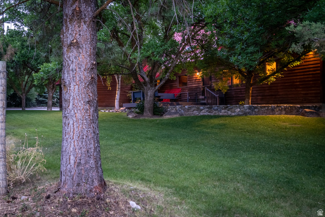 435 Canyon Road Millville, UT 84326 - Photo 73 of 113 Expansive green lawn with mature trees and a stone retaining wall