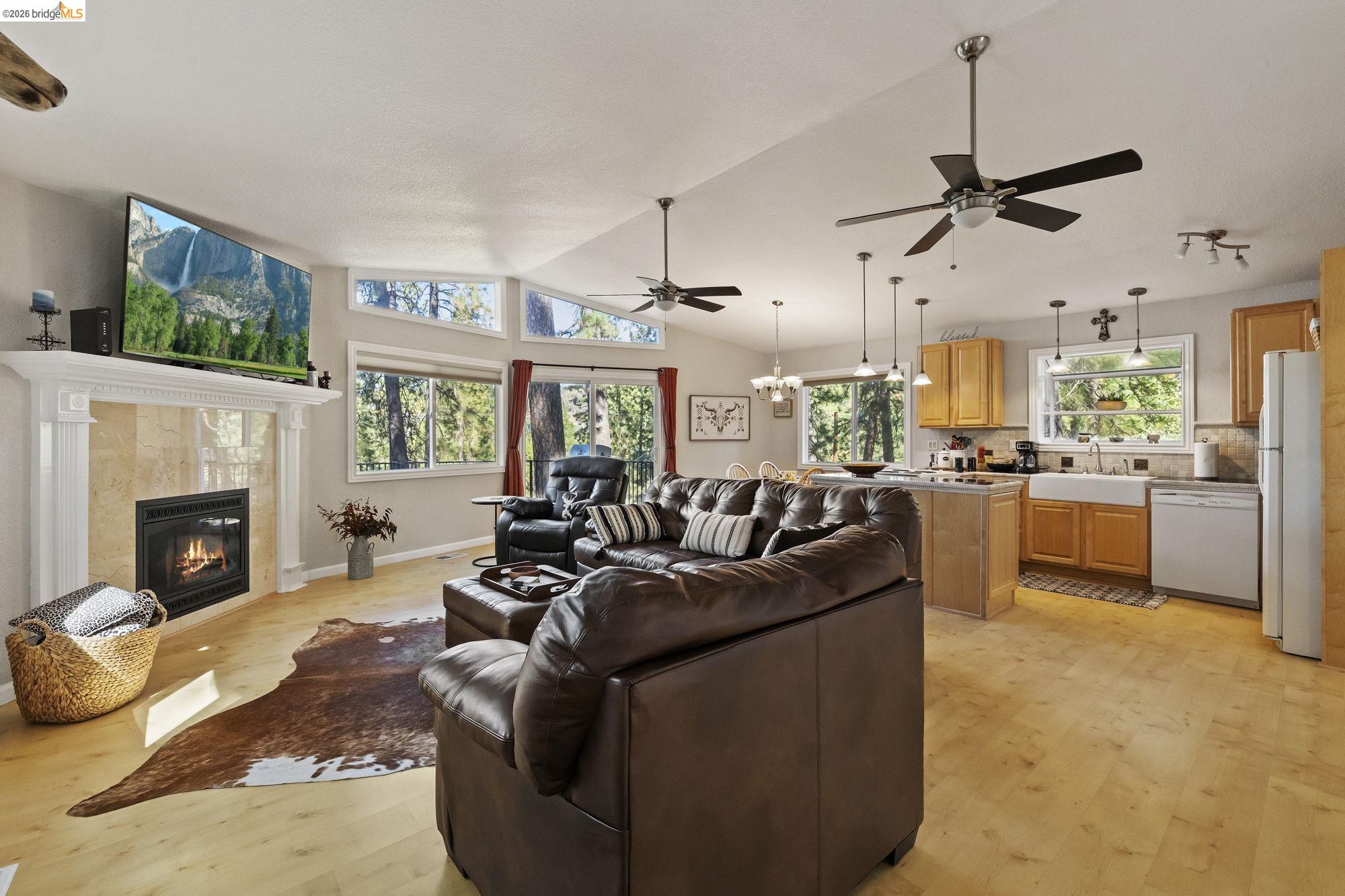 19369 Ferretti Road Groveland, CA 95321 - Photo 7 of 45 Living area with light wood-type flooring, a tiled fireplace, ceiling fan, vaulted ceiling, and a chandelier