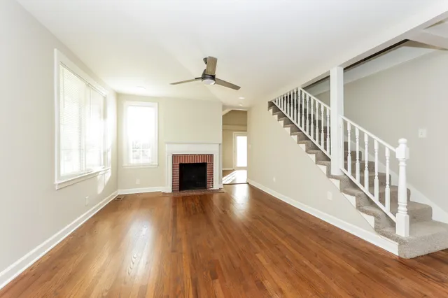 a view of an empty room with wooden floor fireplace and a window
