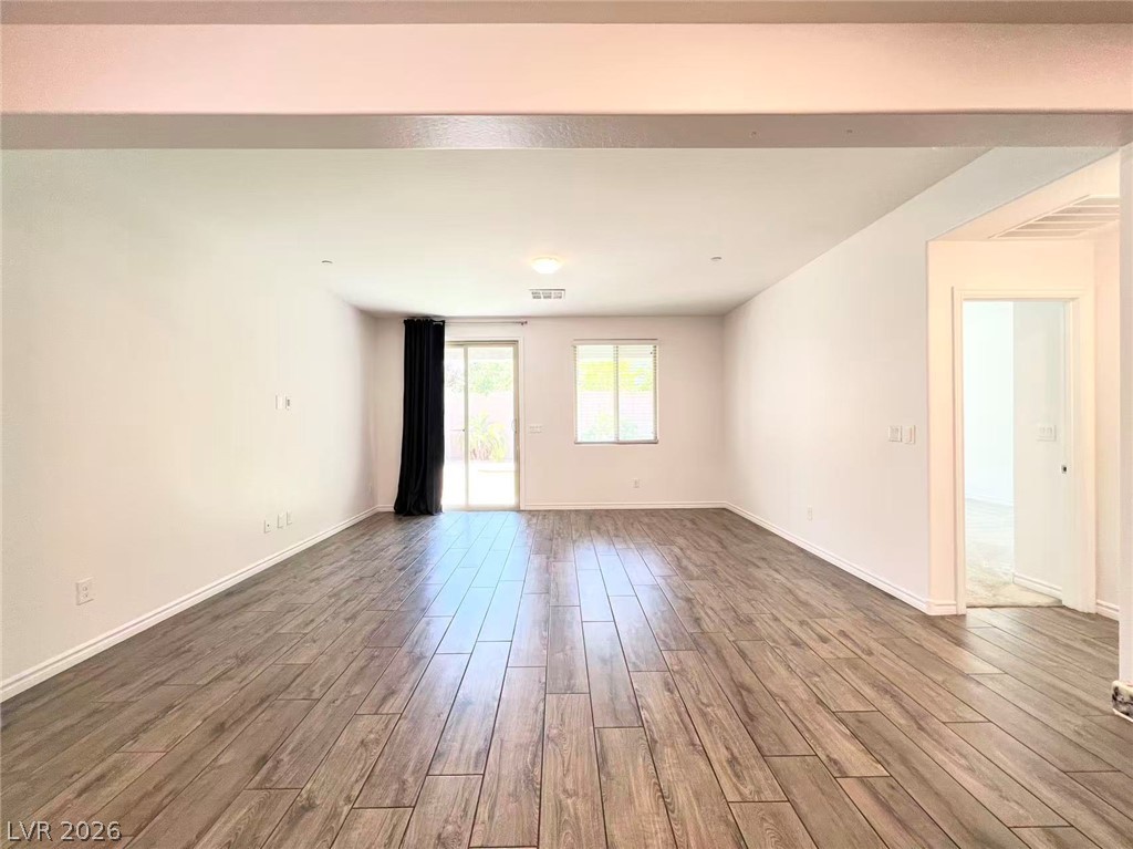925 Bayberry Ridge Street Henderson, NV 89052 - Photo 5 of 27 A spacious living area featuring elegant wood flooring and a sliding glass door leading to outdoor space.