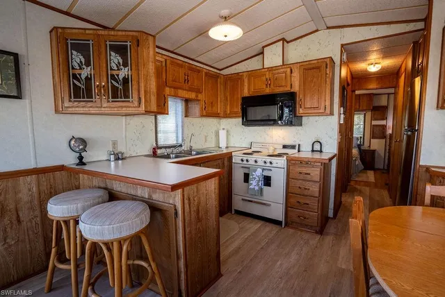 a kitchen with stainless steel appliances a stove a sink dishwasher and a refrigerator with wooden floor