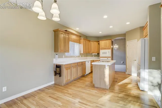 a large kitchen with a sink a counter top space stainless steel appliances and chandelier