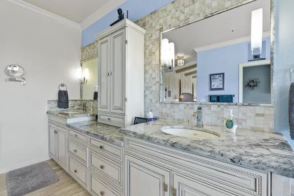 a bathroom with a granite countertop double vanity sink and a mirror